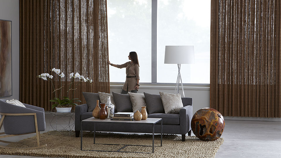 Woman standing backlit infant of window with custom installed drapes