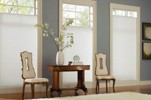 White cellular top down bottom up window shades, one at each of three windows, each adjusted to allow different amounts of light from the tops of the windows